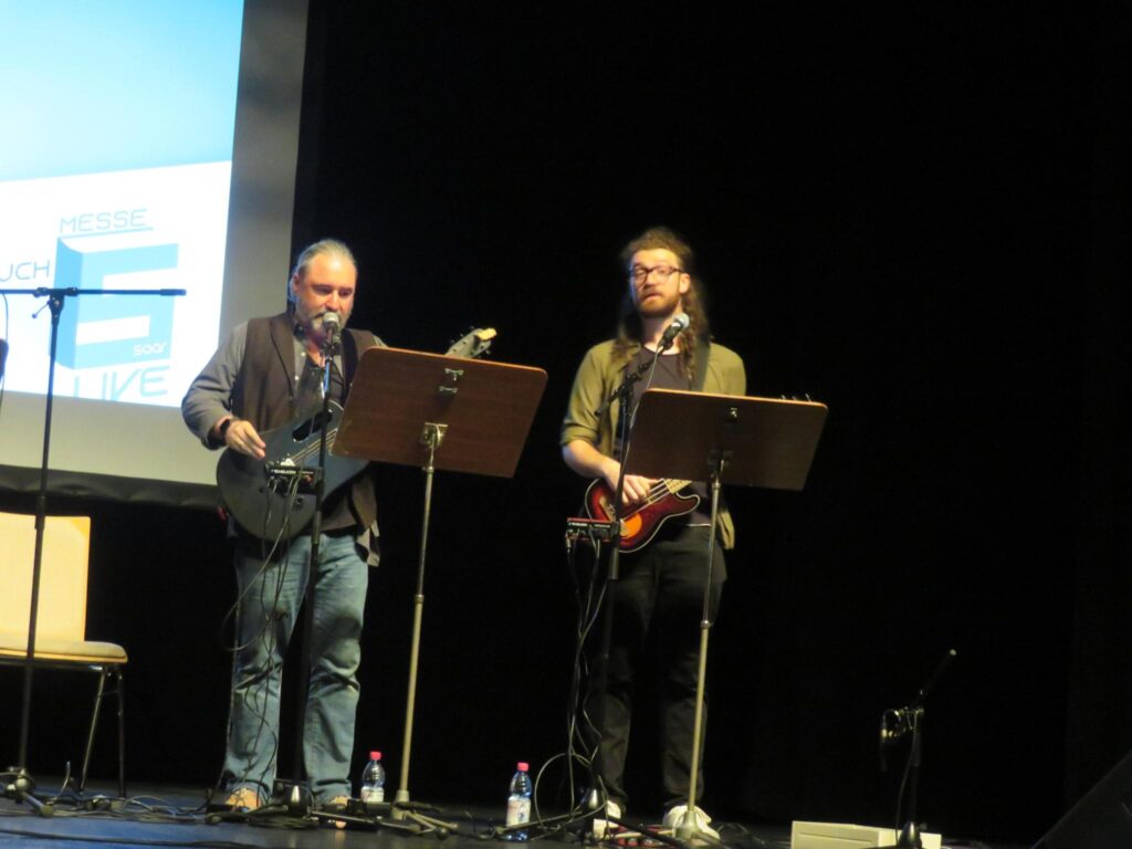Tommy und Muxi stehen mit Gitarren auf der Bühne